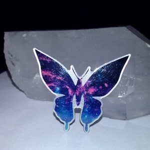 May include: A silver butterfly sticker with a galaxy design featuring shades of blue, purple, and pink.