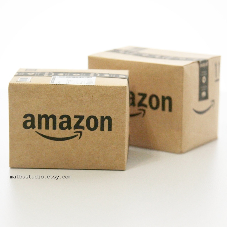 May include: Two brown cardboard boxes with the Amazon logo printed on them. The boxes are stacked on top of each other.