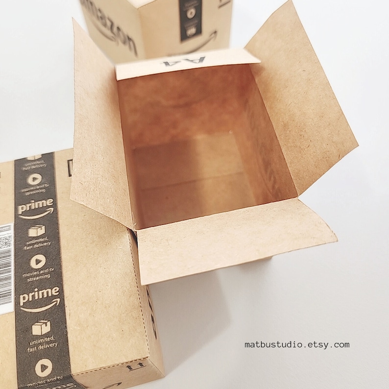 May include: A brown cardboard box with the Amazon logo and the word "prime" printed on it. The box is open and the inside is empty.