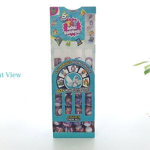 May include: A blue and white cardboard box with a display of small toy capsules. The box has the text "5 Mini Brands!" and "60+ Real Toy Brands to Unbox!" on it.