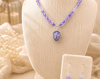 Set di gioielli con perline color lavanda, composto da collana con pendente, bracciale e orecchini realizzati artigianalmente con filo metallico.