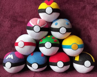 May include: A collection of ten colorful felt balls, each designed with a unique pattern and color scheme. The balls feature white, black, red, yellow, blue, green, and pink accents. Each ball has a white circular design in the center.