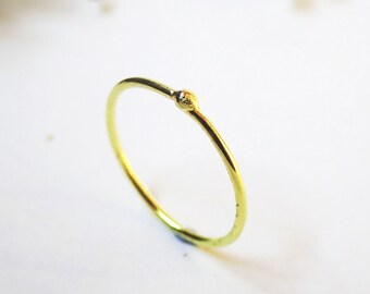 May include: A simple gold ring with a small bead detail.