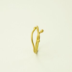 May include: A gold ring with a unique, organic design resembling a branch with small buds. The ring is made of a smooth, polished metal.