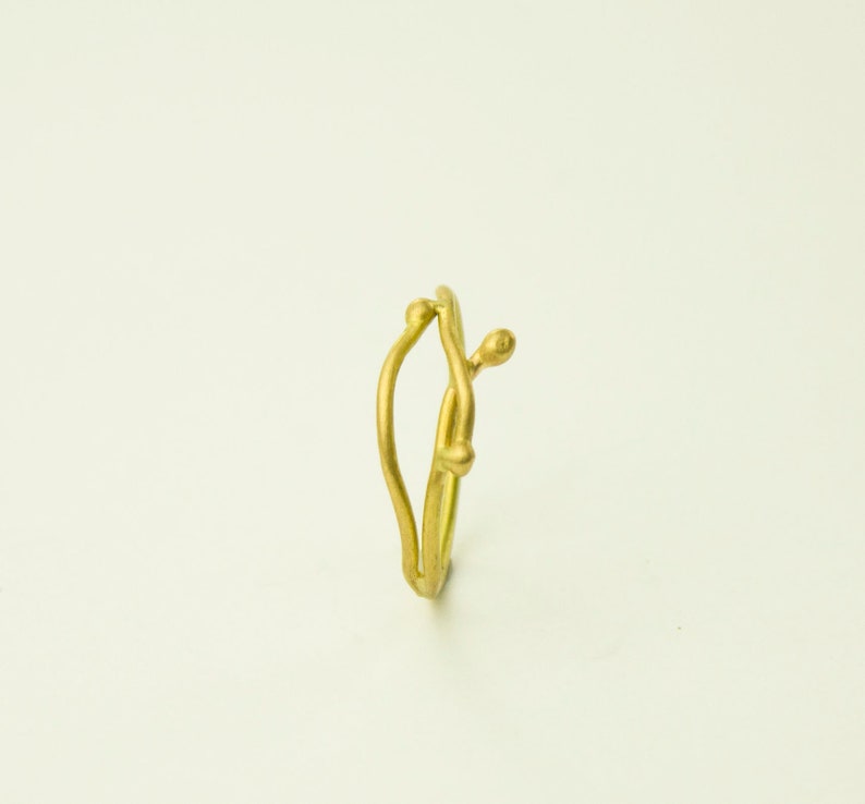 May include: A gold ring with a unique, organic design resembling a branch with small buds. The ring is made of a smooth, polished metal.