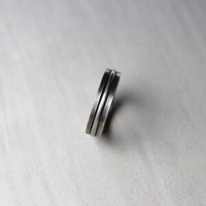 Könnte beinhalten: Ein silberner Ring mit einem Doppelband-Design. Der Ring ist aus Metall und hat eine glatte, polierte Oberfläche.