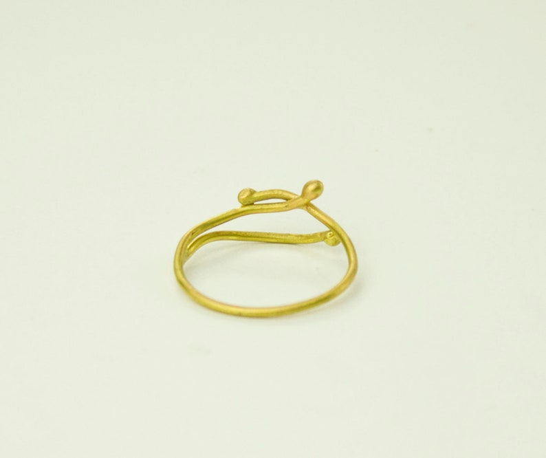 May include: A gold ring with a delicate, twisted design. The ring is made of a single piece of wire that is twisted and shaped to create a unique and modern look.