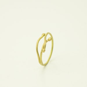 May include: A gold ring with a delicate, twisted design resembling a branch with two small buds.