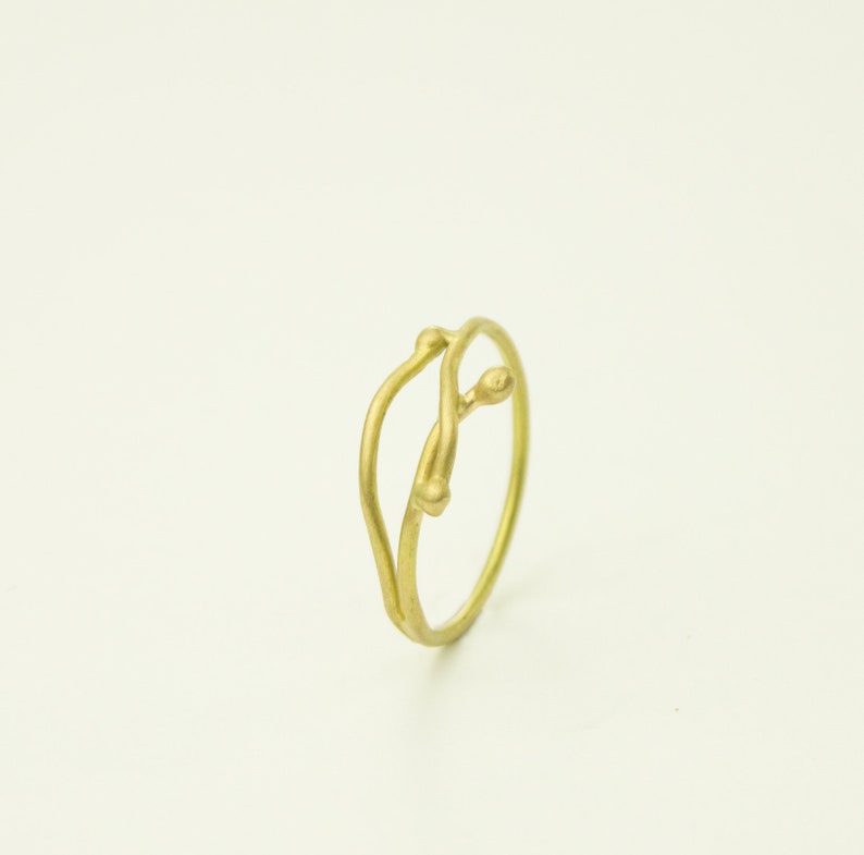 May include: A gold ring with a delicate, twisted design resembling a branch with two small buds.