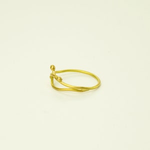 May include: A gold ring with a delicate, organic design. The ring features two intertwined bands with small, rounded accents.