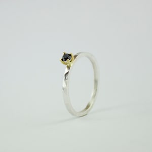 Puede incluir: Un anillo de plata con una banda texturizada y una piedra preciosa negra engastada en un engaste de oro.