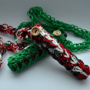 Puede incluir: Dos fundas de botella de ganchillo, una verde y otra roja, blanca y verde. Ambas fundas tienen un botón de madera.