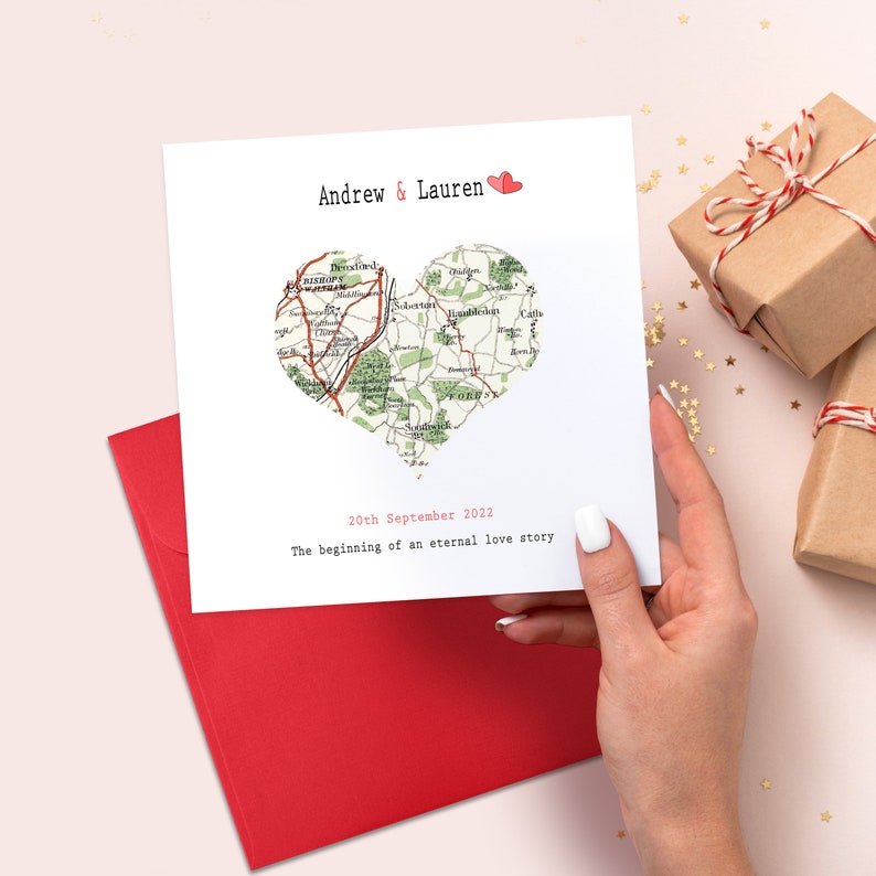 May include: A white card with a red heart and the text "Andrew & Lauren" and "20th September 2022" and "The beginning of an eternal love story". The heart is filled with a map.