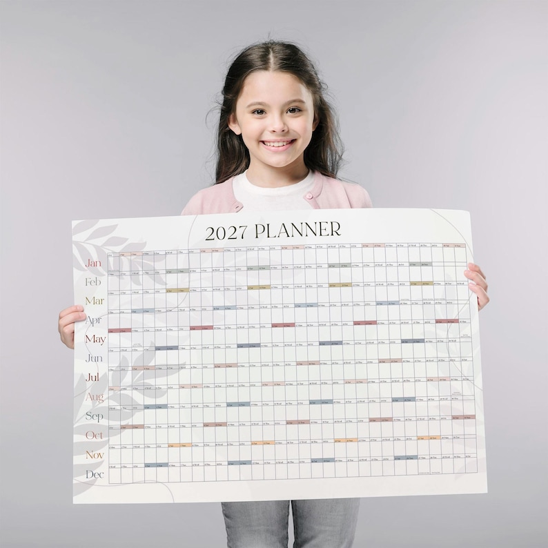 May include: A large wall calendar titled 2027 PLANNER with a grid layout for each month from January to December. The design features a white background with subtle gray leaf illustrations and horizontal rows of colored bars for each month.
