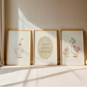 May include: Three framed watercolor prints featuring geese. One print shows a goose with a pink bow, another has the text "Loved Beyond Measure", and the third depicts a goose and a duckling.