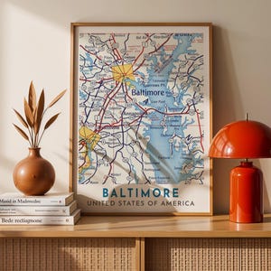 May include: A framed map of Baltimore, Maryland, with a vintage aesthetic. The map shows roads, highways, and waterways, with the city name displayed. The artwork is in a wooden frame, suitable for home decor. The frame is approximately 50 cm x 40 cm.