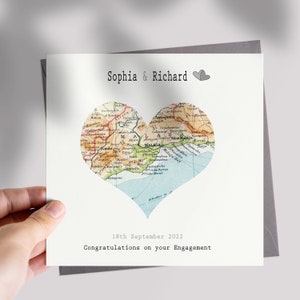 May include: A white card with a map of Spain in the shape of a heart. The card says "Sophia & Richard" and "18th September 2022 Congratulations on your Engagement".