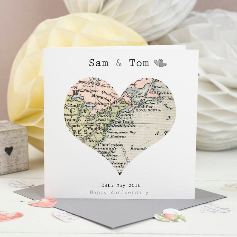 May include: A white card with a heart-shaped map of the United States and Canada. The text "Sam & Tom" and "28th May 2016 Happy Anniversary" is printed on the card.