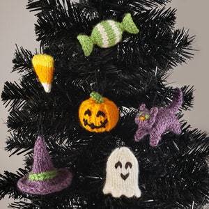 Puede incluir: Un árbol de Navidad artificial negro decorado con adornos de punto de temática de Halloween, que incluyen una calabaza, un fantasma, un sombrero de bruja, un gato negro, un maíz dulce y un bastón de caramelo.