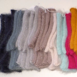 May include: A collection of 14 pairs of fingerless gloves in various colours, including pink, blue, green, and brown. The gloves are made of a soft, fuzzy material and have a delicate, feminine look.