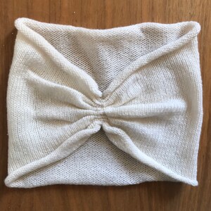 May include: A white knitted headband with a gathered center.