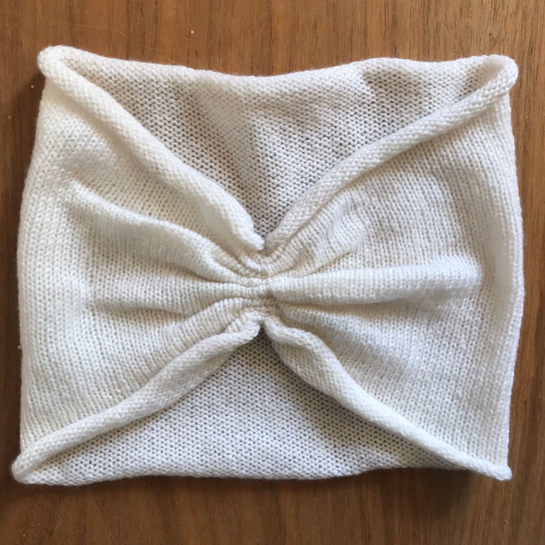 May include: A white knitted headband with a gathered center.