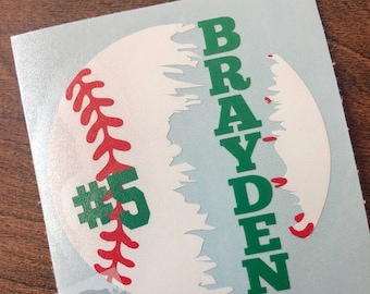 May include: White baseball decal with green and red accents. The decal features the name "BRAYDEN" and the number "#5".