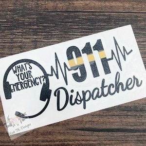 May include: A white sticker with black text that reads "What's Your Emergency?" with a stylized image of a headset. The text "911" is in black with a yellow and black stripe. The text "Dispatcher" is in black.