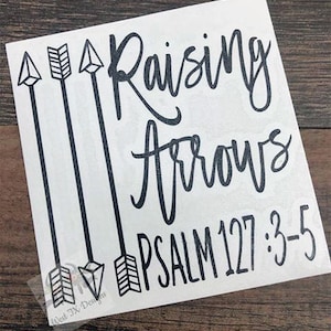 May include: White vinyl decal with black lettering and arrows. The text reads "Raising Arrows Psalm 127:3-5".