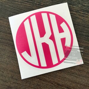 May include: A white vinyl sticker with a pink circle containing the letters "JKA" in a monogram style.