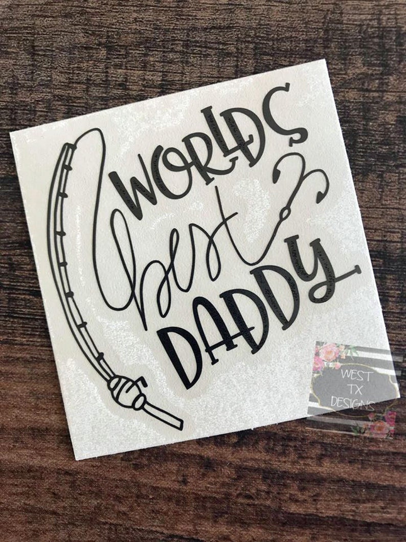 May include: Black and white vinyl decal with a fishing rod and the text "Worlds Best Daddy".