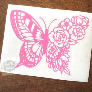 May include: Pink vinyl decal of a butterfly with floral details. The butterfly has intricate wing patterns and is surrounded by roses and other flowers.