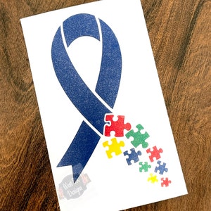 K&ouml;nnte beinhalten: Ein blaues Band mit Puzzleteilen in Rot, Gelb, Gr&uuml;n und Blau, die vom Band herabfallen. Das Band ist ein Symbol f&uuml;r das Bewusstsein f&uuml;r Autismus.