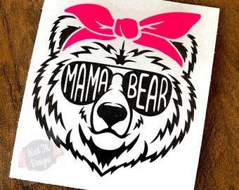 Könnte beinhalten: Ein quadratischer Aufkleber mit einer schwarz-weißen Grafik eines Bärengesichts, das eine Sonnenbrille mit dem Text MAMA BEAR in den Gläsern trägt, sowie einer leuchtend pinken Schleife auf dem Kopf. Ein kleines Logo in der Ecke zeigt West TX Designs.