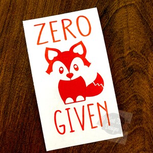 May include: White sticker with red text and a red cartoon fox. The text reads "ZERO GIVEN".