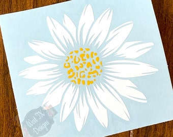 May include: White daisy decal with a yellow leopard print center. The decal is on a light blue background.