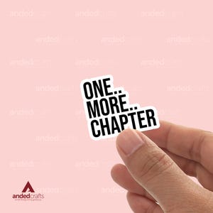 Puede incluir: Una pegatina blanca con texto negro que dice "ONE... MORE... CHAPTER".