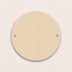 Può includere: Una placca rotonda in legno non rifinita con due fori preforati. La placca è di colore legno chiaro e naturale, e la superficie mostra la venatura del legno. I fori sono distanziati uniformemente vicino al bordo superiore del cerchio.