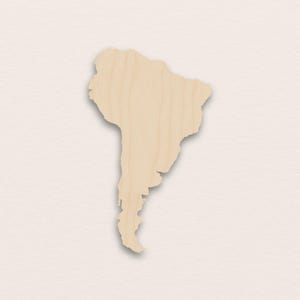 Può includere: Un ritaglio di legno del continente sudamericano. Il ritaglio è marrone chiaro con venature del legno visibili e una leggera ombra, su uno sfondo neutro. La forma è dettagliata.