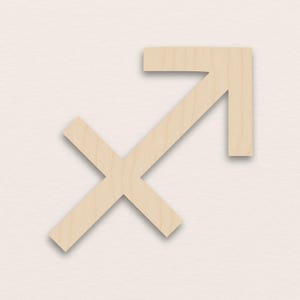Puede incluir: Símbolo de Sagitario de madera, con un diseño estilizado de flecha y cruz. La madera de color claro tiene una veta natural, y el símbolo se encuentra sobre un fondo neutro. Este signo zodiacal se usa a menudo en astrología.
