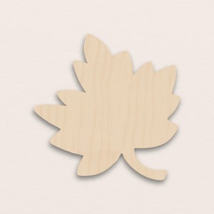 Può includere: Un ritaglio di foglia di legno con finitura naturale venata. La foglia ha una forma dettagliata con più lobi e un gambo. Il ritaglio è probabilmente destinato all'artigianato o alla decorazione.