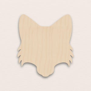 Puede incluir: Recorte de madera con forma de cabeza de zorro. La madera clara muestra la veta. La cabeza de zorro tiene orejas puntiagudas y una estructura facial detallada. Ideal para proyectos de manualidades y aficionados al bricolaje.