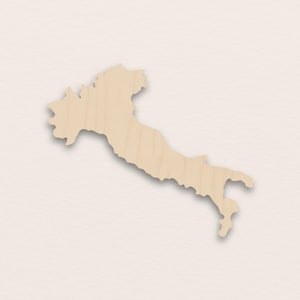 Op de afbeelding: Een houten uitgesneden vorm van Italië, met een lichte houtnerf. De uitgesneden vorm is een gedetailleerde weergave van de kustlijn en vorm van het land, met een subtiel schaduweffect. De achtergrond is een neutrale, gebroken witte kleur.