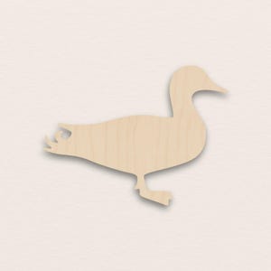 May include: A wooden duck cutout, showing a side profile of a duck. The duck is light brown with visible wood grain. The cutout is designed to stand alone. Suitable for craft projects or home decor.