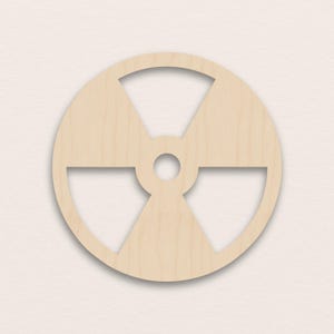 May include: A wooden radiation symbol, a circular design with three blades radiating from a central point. The symbol is cut from light-coloured wood, with a natural wood grain visible. The design is a common warning sign.