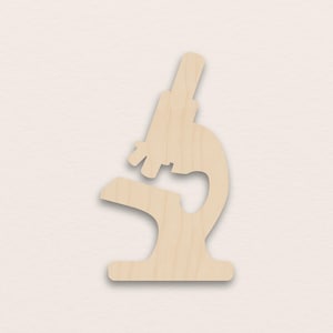 Op de afbeelding: Houten uitsparing van een microscoop. De microscoop is lichtbruin met een eenvoudig ontwerp, bestaande uit een voet, een gebogen arm en een schuin oculair. De uitsparing staat tegen een neutrale achtergrond.