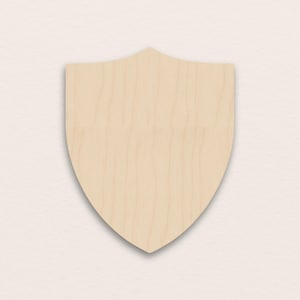 Puede incluir: Un escudo de madera en blanco con una veta de madera clara. El escudo tiene una parte inferior puntiaguda y una parte superior curvada, adecuado para la artesanía o la decoración. El escudo es de color madera natural.