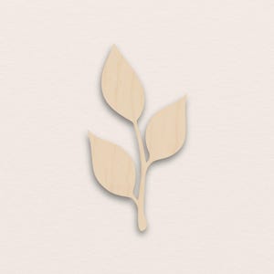 Op de afbeelding: Een houten blad takje met drie bladeren. De bladeren zijn lichtbruin en hebben een natuurlijke houtnerf. Het takje is een decoratief element, mogelijk voor knutselen of woondecoratie.