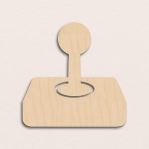 May include: A wooden joystick cutout, featuring a rectangular base with rounded corners and a circular opening. A stem extends upwards, culminating in a circular handle. The natural wood grain is visible.
