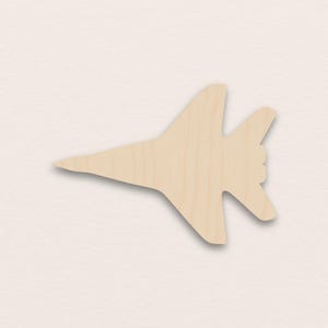 May include: A light brown wooden cutout of a jet aircraft. The aircraft has a pointed nose, a wide body, and angled wings. The tail section features two vertical and two horizontal stabilizers.